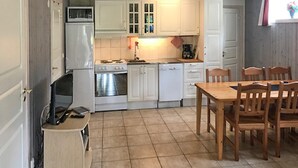 A compact kitchen with white cabinets, a stove, oven, microwave, and a small dining table with wooden chairs. - Nice apartment in Sälen with sauna (Sälen)