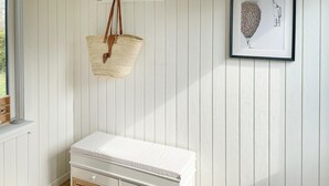 A white room with a white bench, a hanging woven basket, and a framed artwork on the wall. - 2 bedroom lovely home in Dannemare (Dannemare)