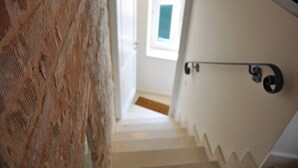 A staircase with white walls and a wooden floor leading to a room with a window. - Room-room With the City and sea View (Split)