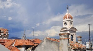 A church with a bell tower and a cross on top, surrounded by buildings with red-tiled roofs. - Room-room With the City and sea View (Split)