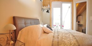A bedroom with a large bed, a bedside lamp, and a view of the outside balcony. - Room-room With the City and sea View (Split)