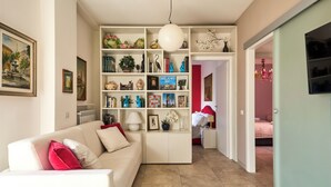 A living room with a white sofa, a bookshelf, and a hallway leading to another room.