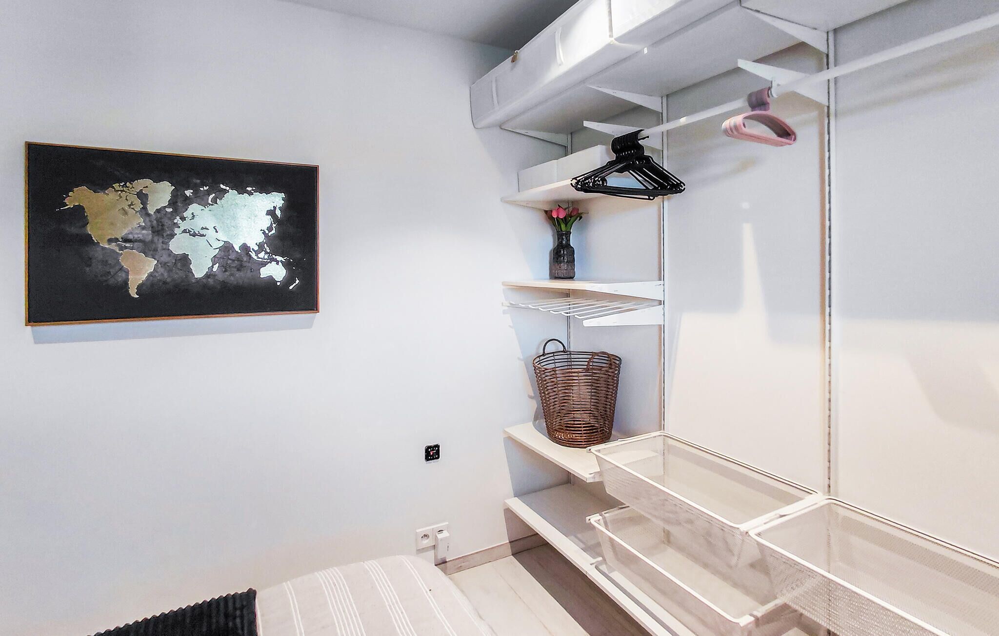 Een modern interieur met een wereldkaart schilderij, een rieten mand en een hangende zwarte kleerhanger.