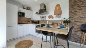 A modern kitchen with white cabinets, a wooden countertop, and a dining area with two chairs. - 1 bedroom lovely apartment in Visé (Visé)