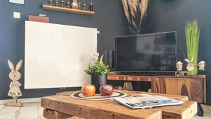 A living room with a wooden coffee table, a television, and decorative items including a plant and figurines. - 1 bedroom lovely apartment in Visé (Visé)