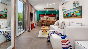 A modern living room with a sofa, a dining table, and a kitchen area.