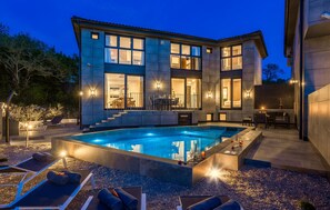 Une maison moderne à deux étages, dotée d’une piscine, d’un espace extérieur aménagé et d’un intérieur bien éclairé.