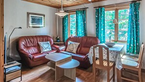 A cozy living room with a leather sofa, a wooden coffee table, and a dining area with a table and chairs. - 1 bedroom stunning home in Gamleby (Gamleby)