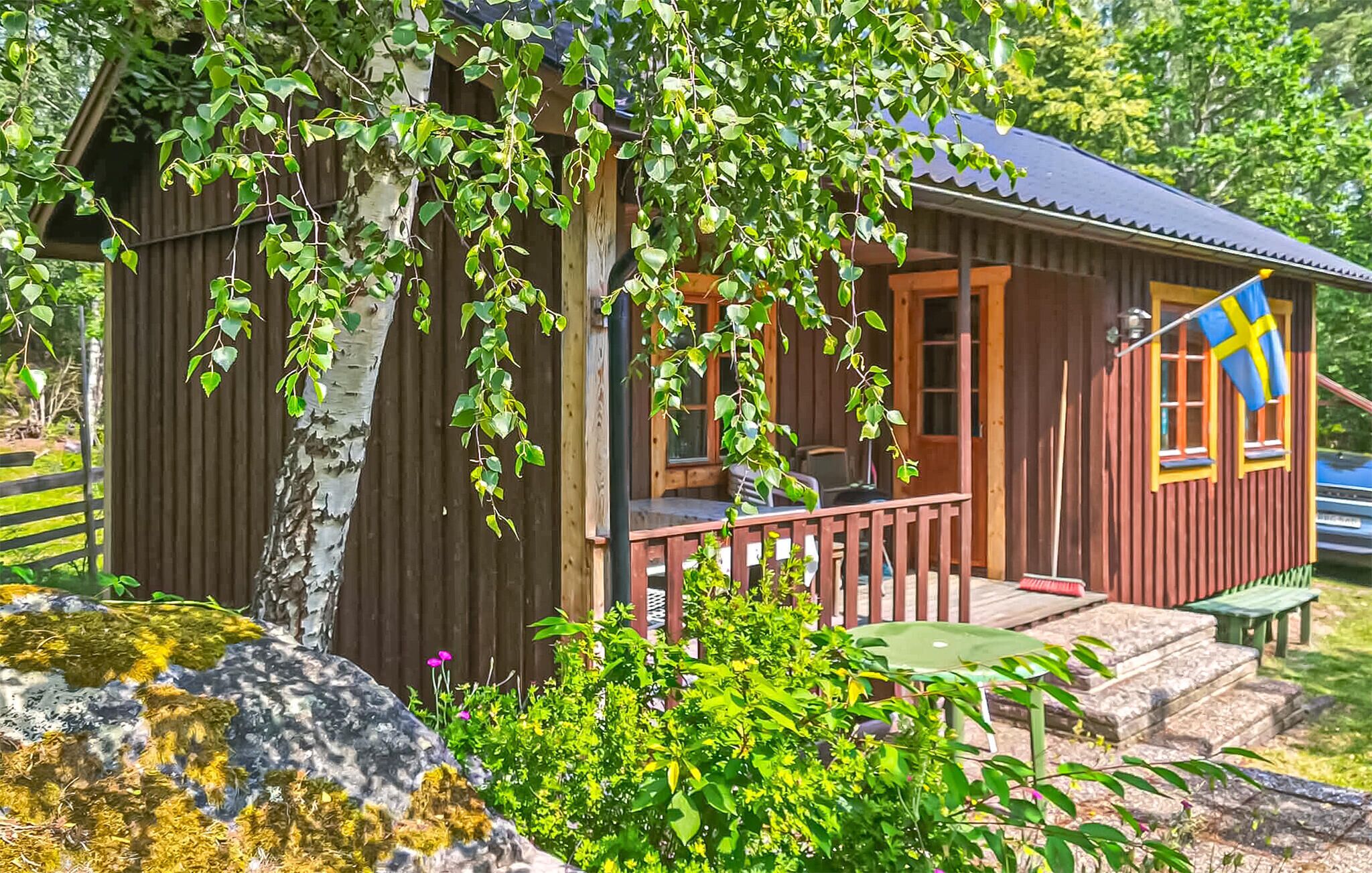 A wooden cabin with a porch, a flag, and a stone bench.