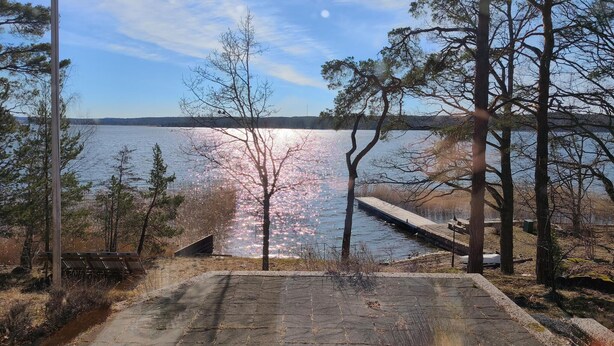 A stone pathway leading to a dock over water, surrounded by trees and a clear sky. - 1 bedroom stunning home in Gamleby (Gamleby)