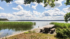 A lakeside picnic area with a wooden dock and benches. - 1 bedroom stunning home in Gamleby (Gamleby)