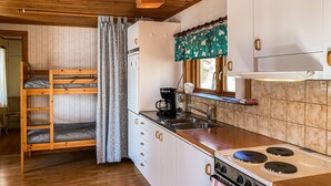 A compact kitchen with a stove, sink, and a window above the counter. A bunk bed is visible in the background. - 1 bedroom stunning home in Gamleby (Gamleby)