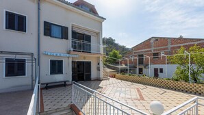 Ein zweistöckiges Gebäude mit Balkon, Treppe und einer gefliesten Terrasse.