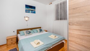 Ein Schlafzimmer mit einem Bett, einem Nachttisch, einer Wandlampe und einem Gemälde.