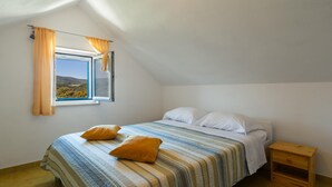 A bedroom with a bed, pillows, a nightstand, and a window with curtains.