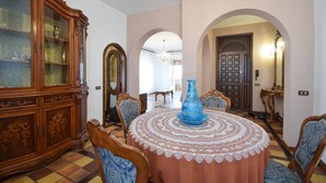 A dining room with a round table, chairs, a blue vase, and a wooden cabinet.