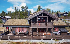 A wooden chalet with a thatched roof, a balcony, and a covered outdoor seating area. - Stunning home in Nissedal with sauna (Nissedal)