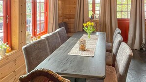 A wooden dining room with a rectangular table, cushioned benches, and a vase of yellow flowers.