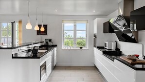 A modern kitchen with white cabinetry, black countertops, and pendant lighting. - Stunning home in Fjerritslev with sauna (Fjerritslev)