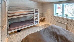 A bunk bed room with a window, a small table, and a heater.