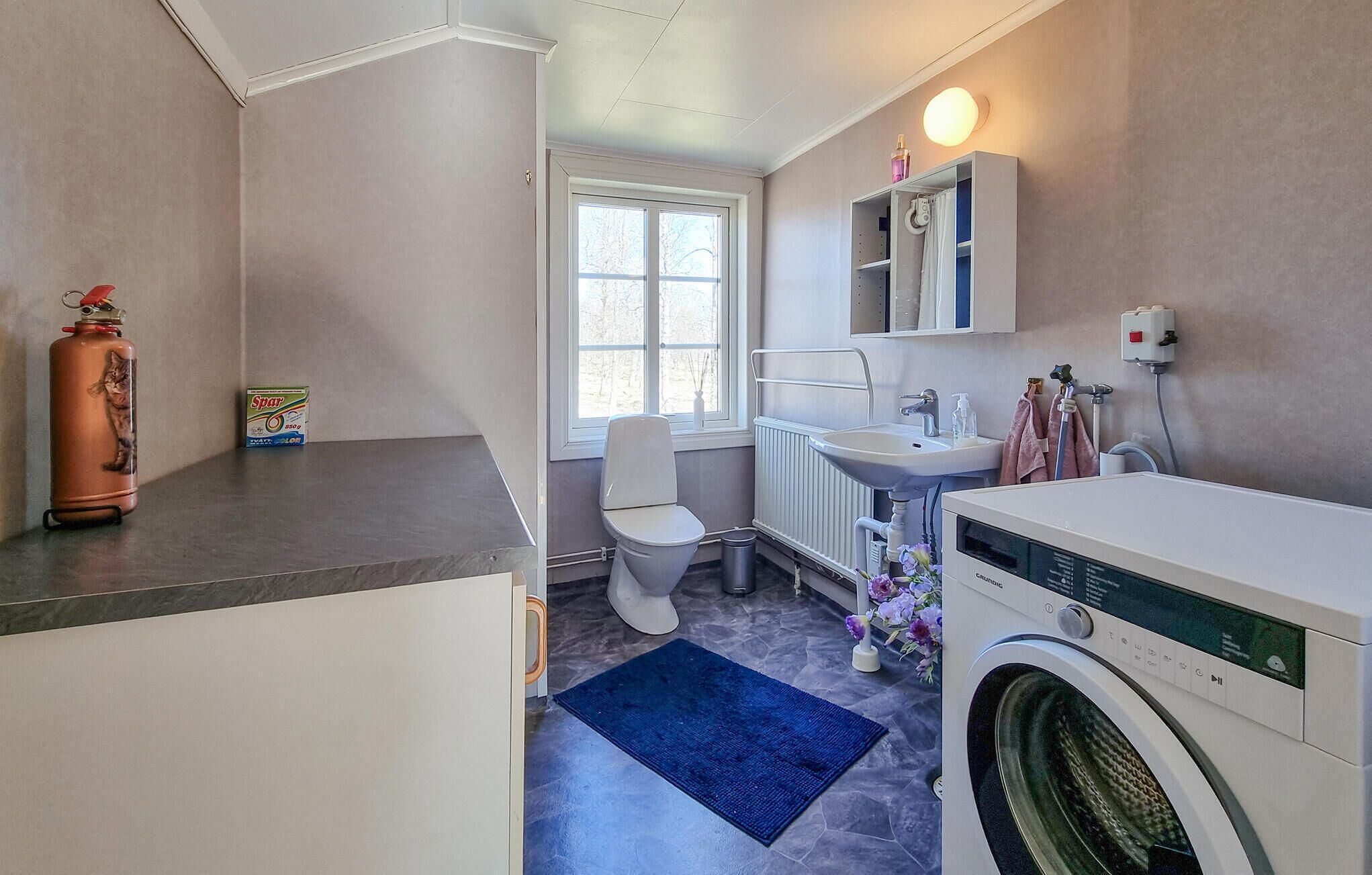 Een kleine badkamer met toilet, wastafel en wasmachine.