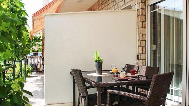 An outdoor patio with wicker furniture, a small table with a potted plant, and a glass door leading to a brick building. - Lovely apartment in Vodice with WiFi (Vodice)