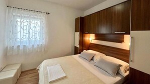 A hotel room with a bed, bedside tables, a window with curtains, and wooden headboard. - Lovely apartment in Vodice with WiFi (Vodice)