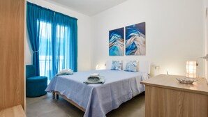 Quarto de hotel com cama, escrivaninha, cadeira e obras de arte na parede.