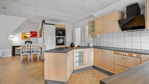 A modern kitchen with wooden cabinets, a black countertop, and a built-in oven. - Cozy apartment in Varde with WiFi (Varde)