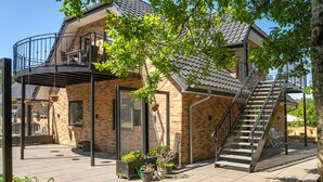 A two-story house with a balcony, a staircase, and potted plants. - Cozy apartment in Varde with WiFi (Varde)