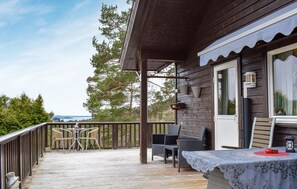A wooden deck with outdoor furniture, a covered area with a table and chairs, and a view of trees and a distant landscape. - Lovely home in Jørpeland with house sea view (Jørpeland)