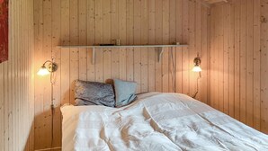 A wooden-paneled room with a bed, two wall-mounted lamps, and a shelf above the bed. - Cozy home in Dronningmølle with WiFi (Dronningmølle)