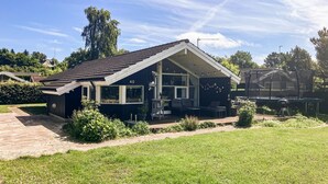 A single-story house with a dark exterior, a tiled roof, and a covered porch area. - Cozy home in Dronningmølle with WiFi (Dronningmølle)