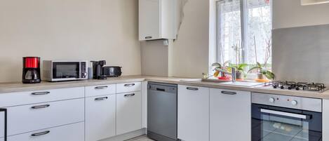 A modern kitchen with white cabinets, a dishwasher, a microwave, a toaster, and a gas stove.