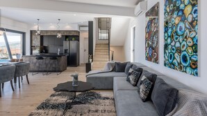 A modern living space with a grey sofa, a coffee table, and a kitchen area with a fridge and a dining table.