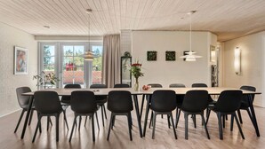 Ett modernt matområde med ett långt bord, svarta stolar och en vas med blommor.