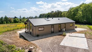 A small, single-story building with a metal roof, a covered porch, and a paved driveway. - 3 bedroom gorgeous home in Haderslev (Haderslev)