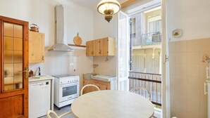 A compact kitchen with wooden cabinets, a stove, oven, and a dining table.