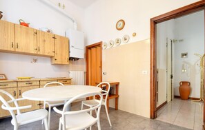 A compact kitchen with wooden cabinets, a white refrigerator, and a dining area with a round table and white chairs. - Amazing apartment in Chiavari with WiFi (Chiavari)