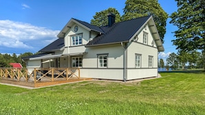 A two-story house with a covered patio and a fenced deck. - Cozy home in Bolmsö with sauna (Bolmsö)