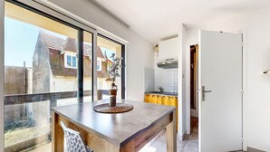 Een moderne keuken met een groot raam, een eettafel met een vaas, en uitzicht op omliggende huizen.