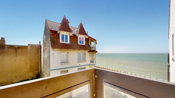 Een gebouw aan de kust met een balkon dat uitkijkt over de zee.