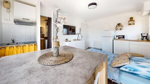 Een moderne keuken met een centraal eiland, een eettafel met stoelen, een magnetron, een koffiezetapparaat en een koelkast.