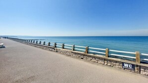Een kustpad met een stenen balustrade, een heldere lucht en de oceaan op de achtergrond.