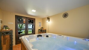 A spa room with a hot tub, wooden furniture, and a view through a glass door.