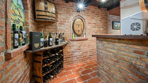 A brick-walled wine cellar with a wooden barrel, wine racks, and a mounted wine bottle.