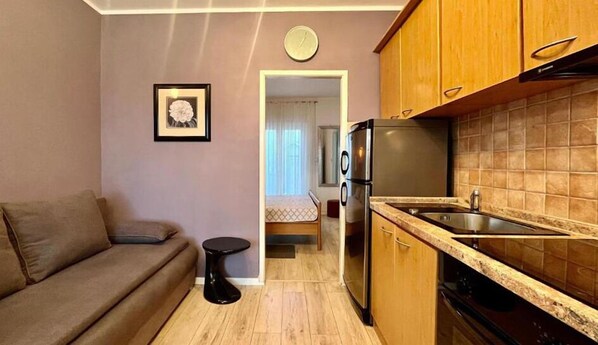 A compact living space with a kitchenette, a sofa, a small round table, and a bed in the background. - Stunning apartment in Vodice with WiFi (Vodice)