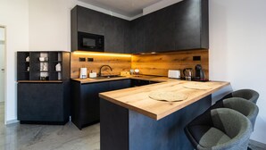 A modern kitchen with dark cabinetry, a wooden island, and a built-in microwave. - 1 bedroom stunning apartment in Hvar (Hvar)