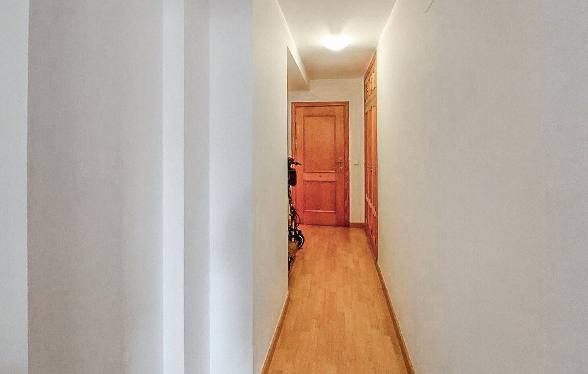 A narrow hallway with wooden flooring and white walls.