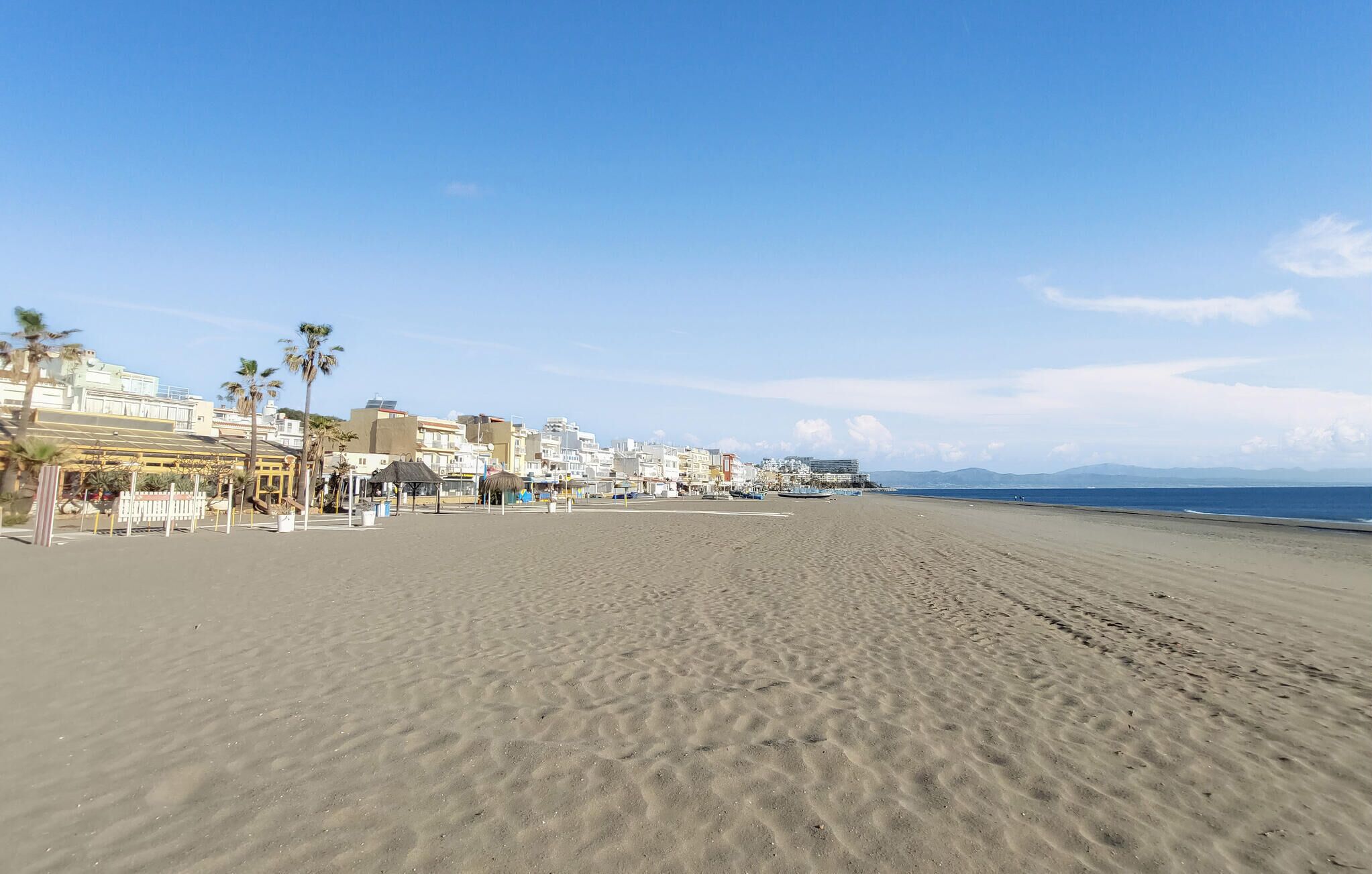 Una amplia playa de arena con edificios al fondo.